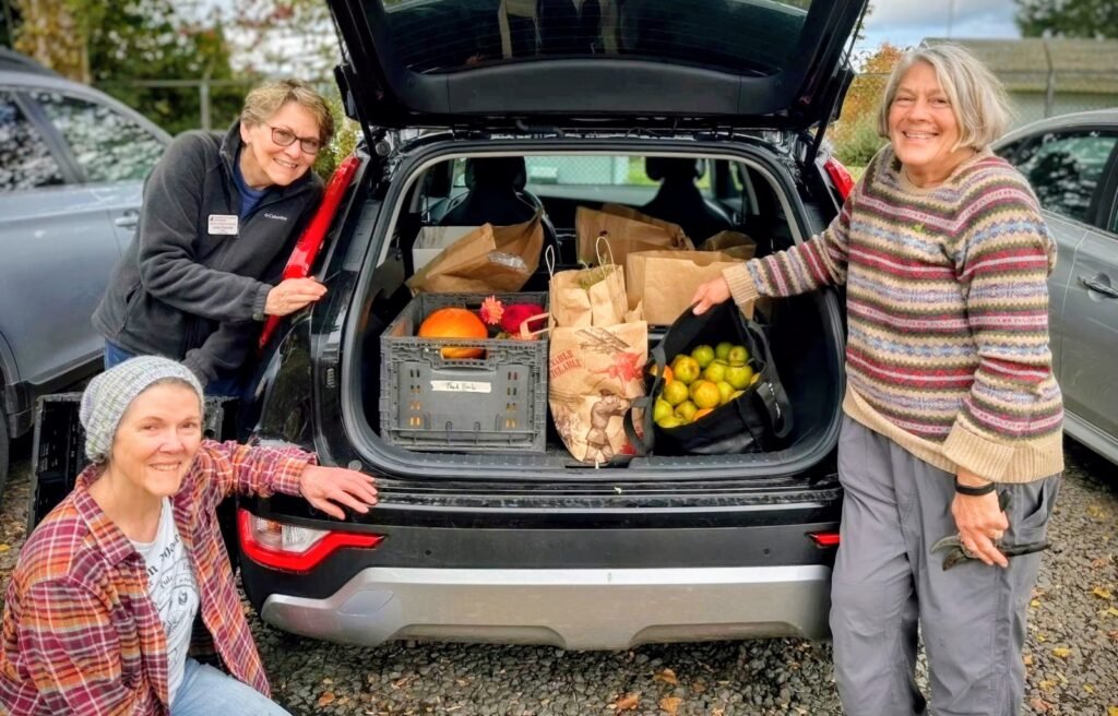 Master Gardener volunteers standing in front of car with harvested fruits and veggies